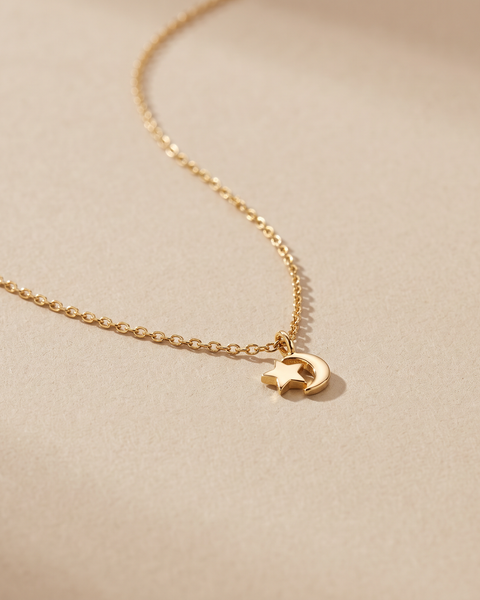 Collar Luna con estrella y luna en oro 18k sobre fondo arena