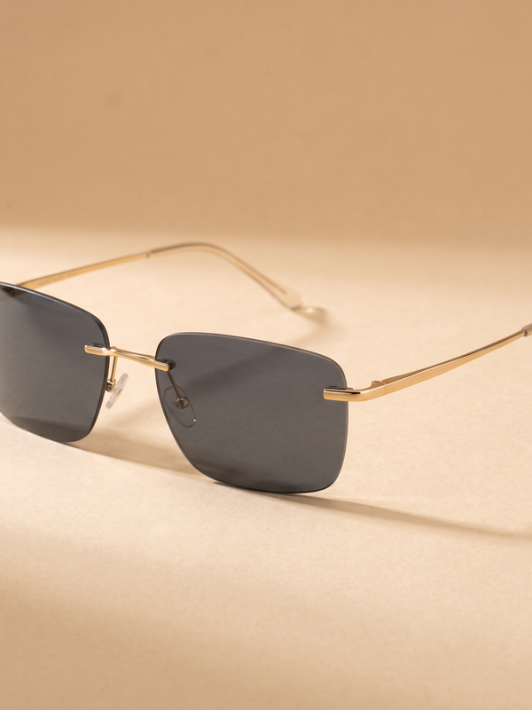 Gafas Faro polarizadas sin montura con varillas doradas sobre fondo arena